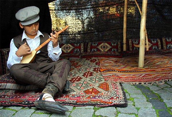 A child playing saz in a tent